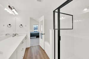 Bathroom featuring wood-type flooring, vanity, and a shower with shower door