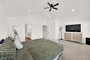 Carpeted bedroom featuring high vaulted ceiling, ceiling fan, and ensuite bathroom