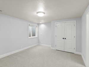 Unfurnished bedroom featuring light carpet, a closet, and a textured ceiling