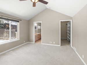 Unfurnished bedroom with ensuite bath, ceiling fan, vaulted ceiling, a walk in closet, and a closet