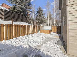 Yard layered in snow featuring a hot tub