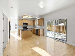 Kitchen with a center island, sink, light hardwood / wood-style floors, and black appliances