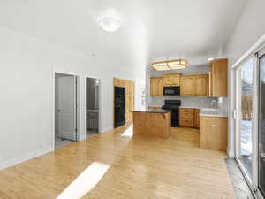 Kitchen featuring sink, black appliances, a center island, and light wood-type flooring