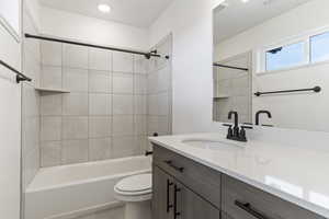 Full bathroom featuring vanity, tiled shower / bath combo, and toilet