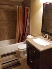 Full bathroom featuring vanity, shower / bath combination with curtain, tile patterned floors, and toilet