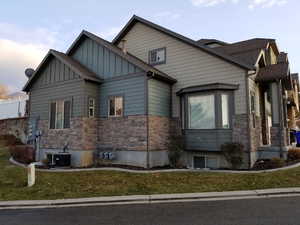 View of front of house with a yard and central AC