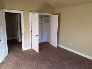 Unfurnished bedroom with lofted ceiling, a closet, and carpet