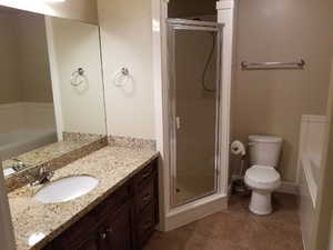 Bathroom with tile patterned floors, vanity, toilet, and an enclosed shower