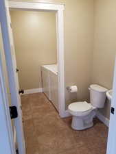 Bathroom with tile patterned flooring, washer and dryer, and toilet