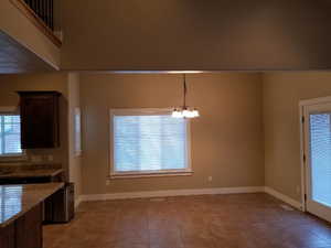 Unfurnished dining area with light tile patterned floors and a chandelier