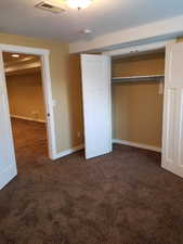 Unfurnished bedroom featuring dark carpet and a closet