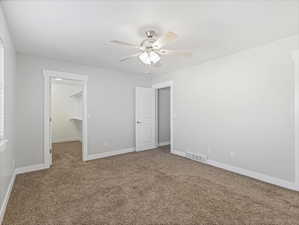 Unfurnished bedroom with ceiling fan, a walk in closet, carpet flooring, and a closet