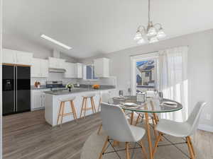 Dining area featuring lofted ceiling, an inviting chandelier, and light wood-type flooring