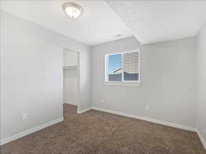 Unfurnished bedroom featuring a walk in closet, carpet, and a closet