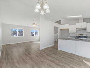 Kitchen featuring white cabinetry, dark stone counters, decorative light fixtures, and stainless steel stove