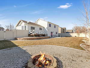 Rear view of house with a wooden deck, an outdoor fire pit, a yard, and a patio