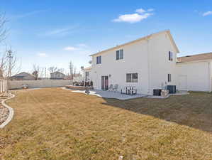 Rear view of property featuring central AC, a lawn, and a patio