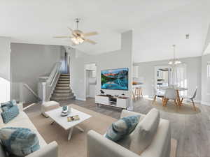 Living room with hardwood / wood-style flooring, ceiling fan with notable chandelier, and high vaulted ceiling