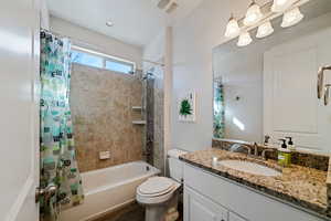 Full bathroom with vanity, hardwood / wood-style floors, shower / tub combo with curtain, and toilet