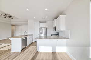 Kitchen featuring white cabinetry, a kitchen breakfast bar, kitchen peninsula, and appliances with stainless steel finishes