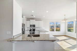 Kitchen with white cabinetry, appliances with stainless steel finishes, a kitchen breakfast bar, and kitchen peninsula