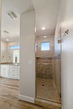 Bathroom featuring vanity, hardwood / wood-style floors, a textured ceiling, and walk in shower