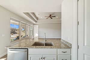 Kitchen with white cabinetry, dishwasher, light stone countertops, and sink