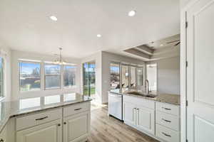 Kitchen featuring sink, decorative light fixtures, white cabinets, and dishwasher