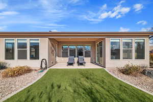 Back of house featuring a lawn and a patio area