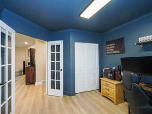 Home office featuring french doors, crown molding, and light wood-type flooring