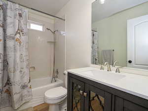 Full bathroom with vanity, toilet, wood-type flooring, and shower / bath combo