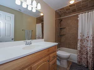 Full bathroom featuring shower / bath combination with curtain, tile patterned floors, vanity, and toilet