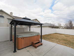 View of patio featuring a hot tub and a gazebo