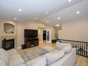 Living room featuring a tiled fireplace, lofted ceiling, and light wood-type flooring