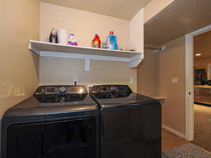 Washroom featuring light tile patterned floors, washing machine and dryer, and a textured ceiling