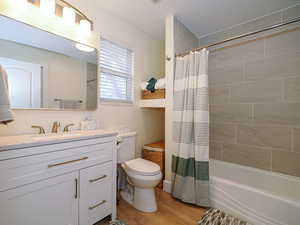 Full bathroom with wood-type flooring, toilet, shower / tub combo, and vanity