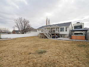 Back of property with a lawn, a gazebo, a wooden deck, a patio area, and a hot tub