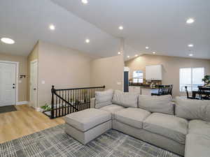 Living room with lofted ceiling, a wealth of natural light, and light hardwood / wood-style floors