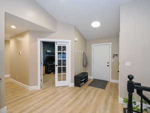 Entrance foyer with french doors and light hardwood / wood-style flooring