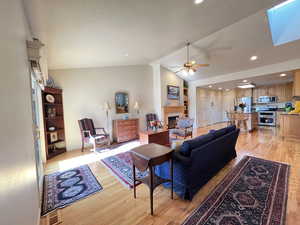 Living room with vaulted ceiling, ceiling fan, and light hardwood / wood-style floors