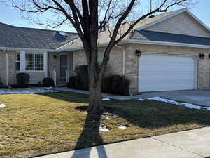 Ranch-style house featuring a garage and a front lawn