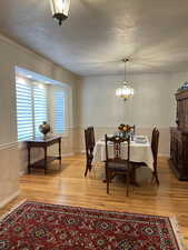 Dining area featuring ornamental molding, a chandelier, light hardwood / wood-style floors, and a textured ceiling