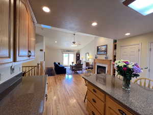 Kitchen featuring a breakfast bar area, vaulted ceiling, a textured ceiling, light wood-type flooring, and a tiled fireplace