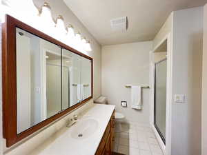 Bathroom with tile patterned floors, vanity, toilet, and an enclosed shower