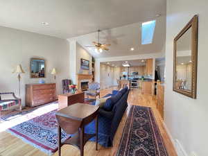 Living room featuring ceiling fan, vaulted ceiling, and light hardwood / wood-style flooring