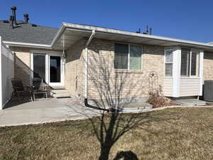 Back of property featuring central AC unit, a patio, and a lawn