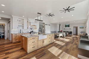 Kitchen featuring sink, hanging light fixtures, a large island with sink, ceiling fan, and a barn door