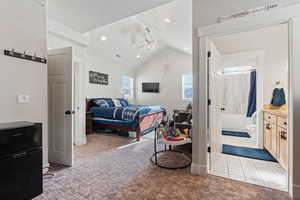 Bedroom with vaulted ceiling, light colored carpet, and ensuite bathroom