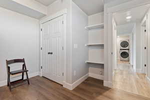 Hall with hardwood / wood-style flooring and stacked washer / drying machine