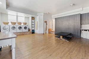 Interior space with cabinets, washing machine and clothes dryer, and light wood-type flooring